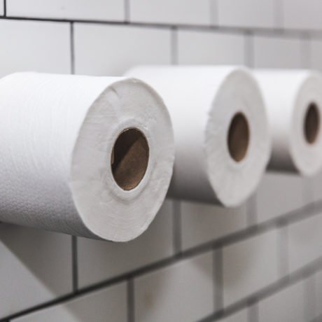 three-rolls-of-toilet-paper-on-white-tile-wall